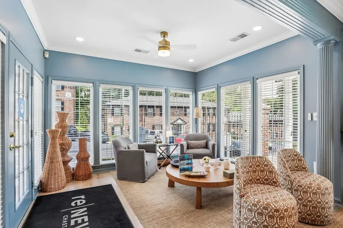 Bright and inviting sitting area with stylish chairs, natural woven decor, and expansive windows for abundant daylight.