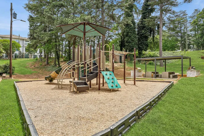 Vibrant community playground nestled in lush greenery, featuring modern play equipment and shaded seating area.