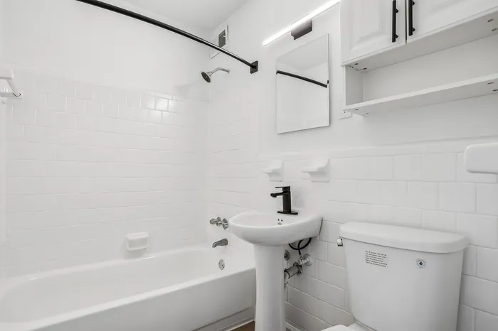Bright and modern bathroom featuring a sleek white bathtub, stylish pedestal sink, and contemporary fixtures.