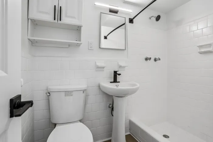 Modern bathroom with sleek fixtures, elegant white tiles, and a spacious shower area.