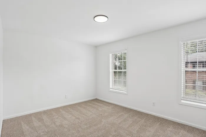 Bright and inviting room with plush carpeting and large windows, perfect for a cozy living space.