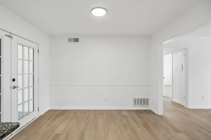 Bright and inviting apartment interior featuring a spacious room with elegant wood flooring and stylish French doors.