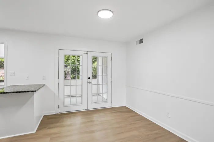 Bright and modern room featuring elegant French doors, sleek hardwood floors, and a stylish granite countertop.