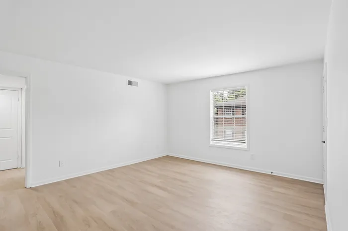 Bright, spacious room with natural light and elegant wood flooring, perfect for a cozy retreat.