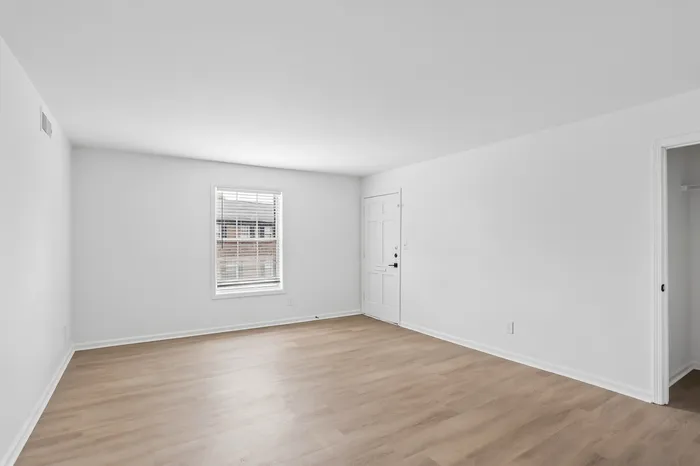 Bright and airy room with elegant wooden flooring and large window, perfect for a cozy living space or stylish office.