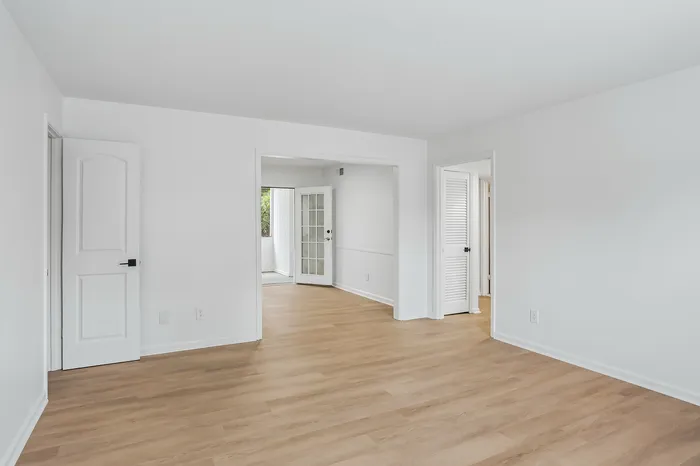 Bright and airy apartment with sleek hardwood floors, open layout, and natural light streaming through glass doors.