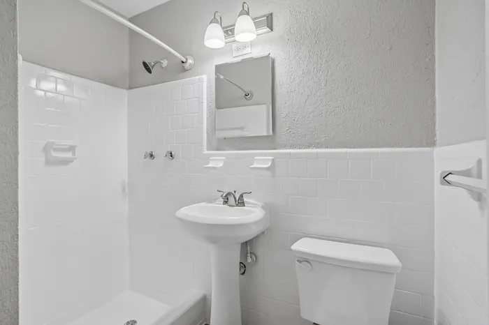 Bright, modern bathroom showcasing elegant fixtures, pristine white tiles, and a stylish pedestal sink.