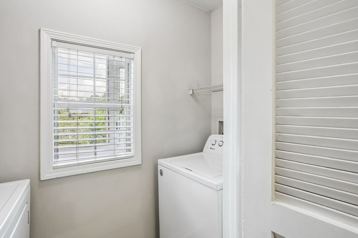 Bright and efficient laundry room with modern washing machine and natural light from a large window.