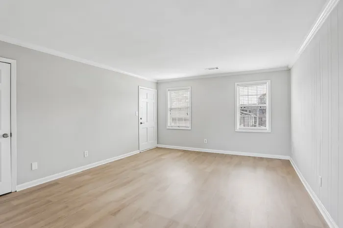 Bright and airy living space with hardwood floors and large windows, perfect for cozy family gatherings.