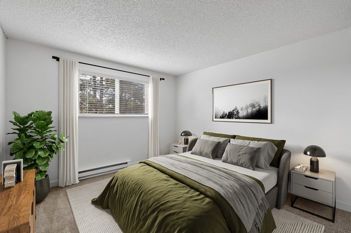 Bright and cozy bedroom featuring a plush bed with green accents, modern nightstands, and a tall potted plant by the window, perfect for relaxation.