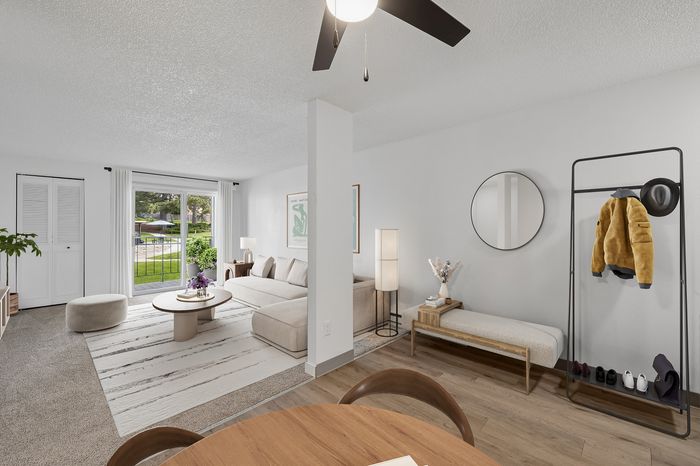 Contemporary living room with a cozy beige sofa, large window view, elegant minimalist decor, and stylish hardwood floors.
