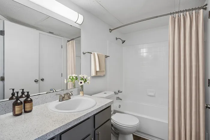 Modern bathroom featuring sleek countertops, elegant fixtures, and a polished bathtub, complemented by fresh floral accents.