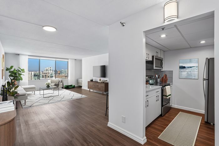 Elegant urban apartment with an open-concept living area, featuring large windows with cityscape views, a modern kitchen with sleek appliances, and stylish hardwood flooring.