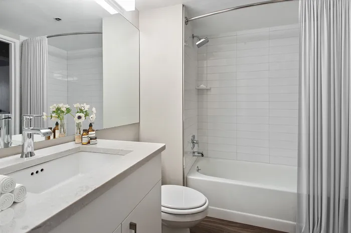 Elegant modern bathroom with sleek white vanity, polished chrome fixtures, and a luxurious bathtub accented by soft lighting.