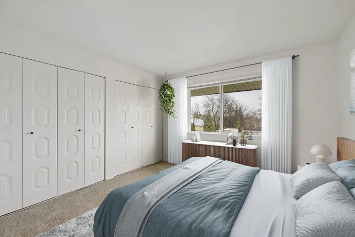 Bright and inviting bedroom with large window, modern decor, and ample closet space.