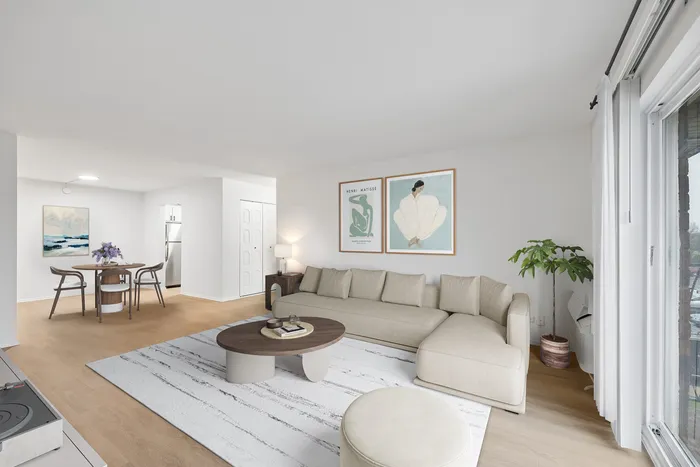 Bright and inviting living room with a modern beige sectional, stylish artwork, and a cozy dining space with natural light.