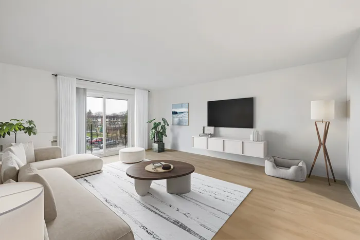 Modern living room with sleek decor, featuring a large sectional sofa, stylish coffee table, and a wall-mounted TV. Abundant natural light from wide windows with a captivating outdoor view.