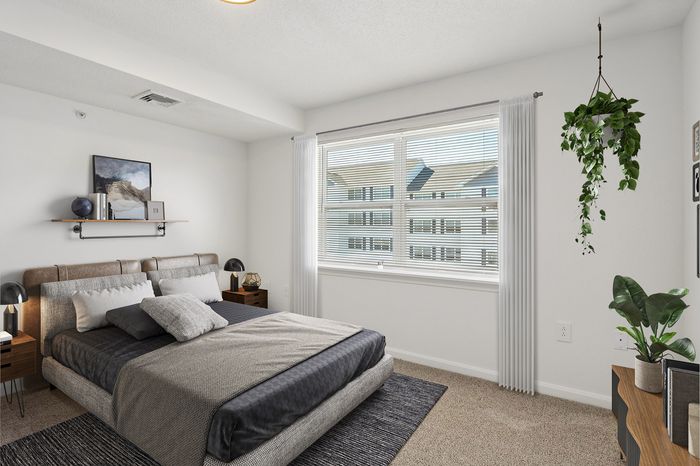 Bright and modern bedroom featuring stylish decor, luxurious bed, and large window with a view, accented with indoor plants for a serene ambiance.