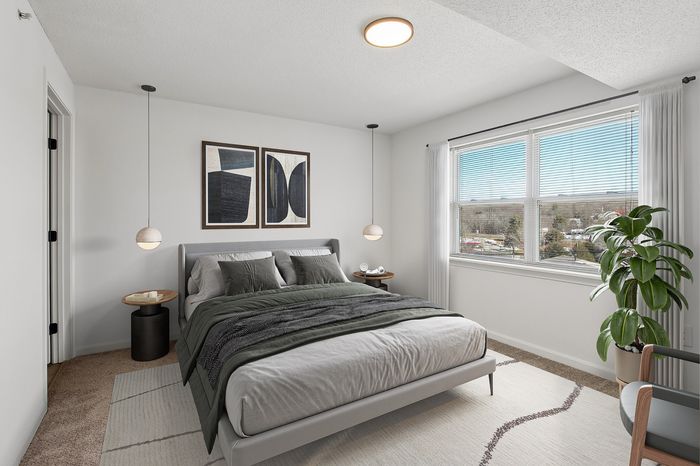 Bright and inviting bedroom with modern decor, plush bedding, large window offering natural light, and stylish wall art.
