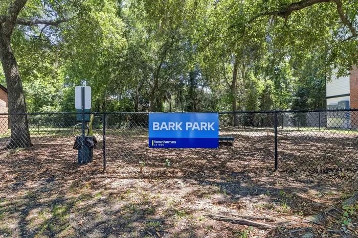 Charming park area for dogs, nestled beneath lush green trees, providing a serene environment for pet-friendly townhomes.