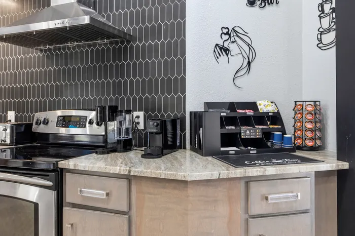 Modern kitchen corner featuring a sleek coffee bar with a stylish backsplash, stainless steel appliances, and an organized coffee station.