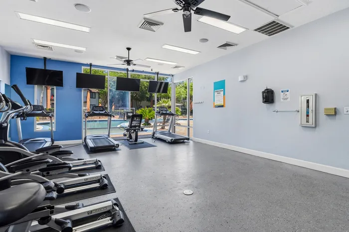 Modern fitness center with state-of-the-art exercise equipment and pool view, perfect for an active lifestyle.