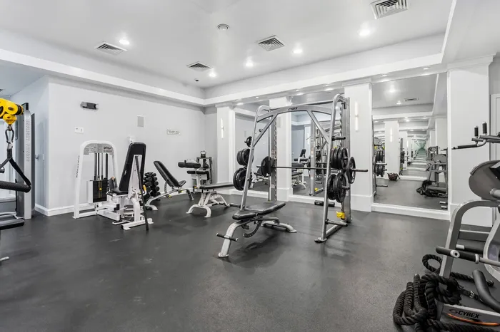 Modern and spacious fitness center featuring state-of-the-art gym equipment and mirrored walls ideal for an invigorating workout experience.
