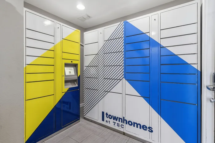 Modern package locker room with vibrant blue and yellow geometric design at townhomes, featuring digital screen for secure access.
