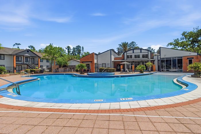 Inviting apartment complex showcasing a sparkling outdoor swimming pool surrounded by lush greenery and modern architecture.