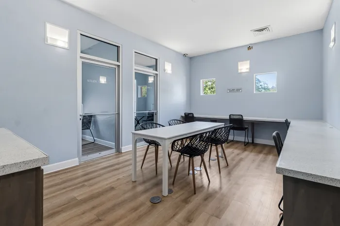 Modern study room with elegant black chairs, sleek white tables, and natural light from large windows.