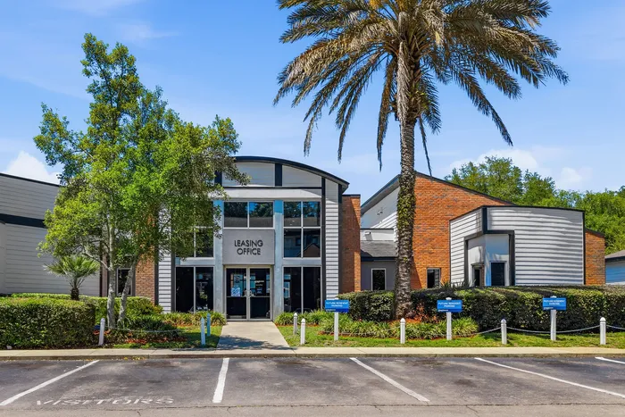 Inviting leasing office with modern architecture, surrounded by lush greenery and palm trees, offers a welcoming atmosphere for visitors.