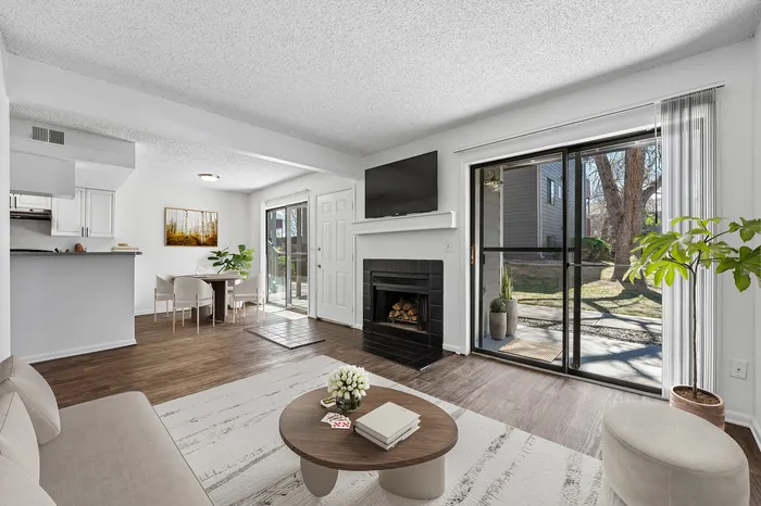 Bright and inviting living area with a modern fireplace, elegant decor, and large sliding glass doors leading to a serene outdoor view.