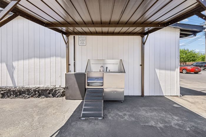 Outdoor covered car wash area with metal roof and sleek stainless steel sink, perfect for convenient vehicle maintenance.