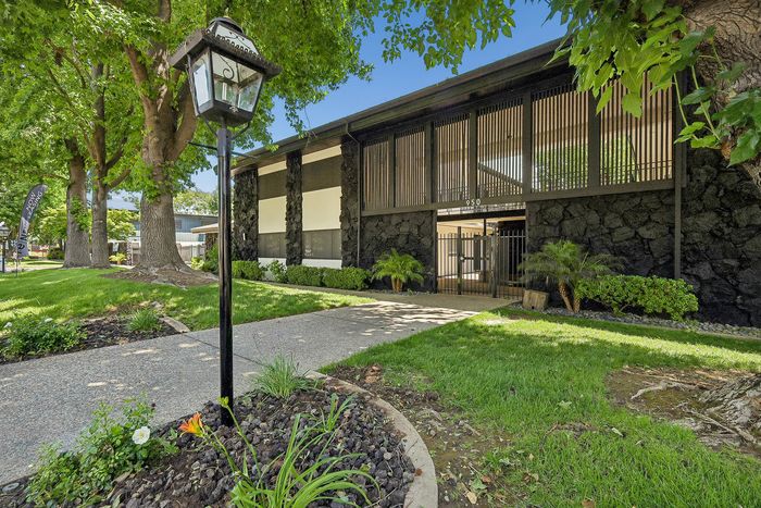 Charming apartment exterior with lush greenery, elegant stone accents, and stylish architectural design.
