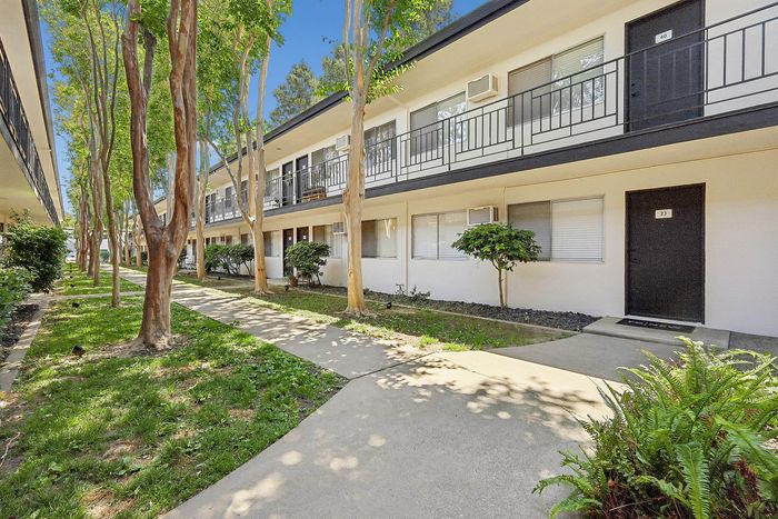 Modern apartment complex with lush greenery and ample natural light, featuring a clean and inviting facade.