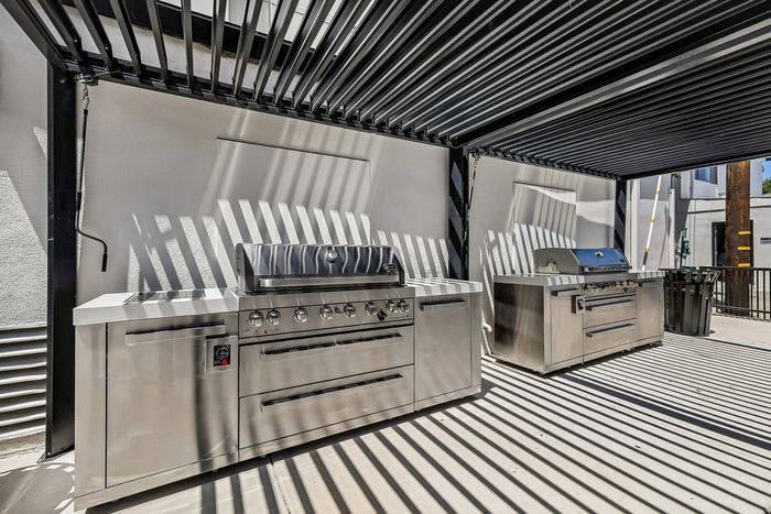Chic outdoor grilling station with modern stainless steel barbecue setup under stylish pergola.