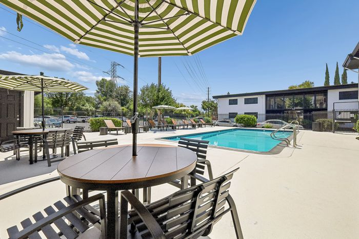 Inviting outdoor space with a sparkling pool, stylish patio seating, and vibrant greenery, perfect for relaxation and social gatherings.