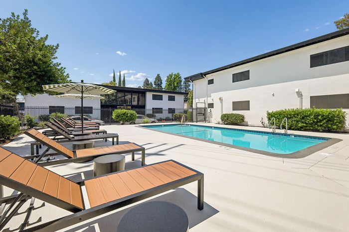 Bright and inviting outdoor pool area with modern lounge chairs and lush greenery, ideal for relaxation and soaking in the sunshine.