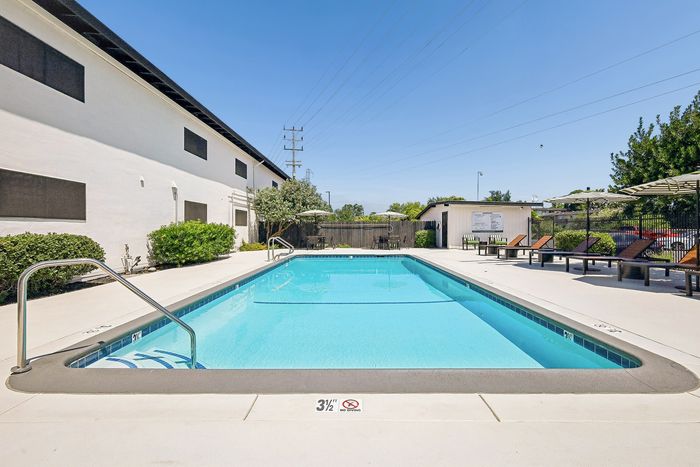 Inviting outdoor pool area with relaxing lounge chairs and vibrant greenery, perfect for a sunny day retreat.