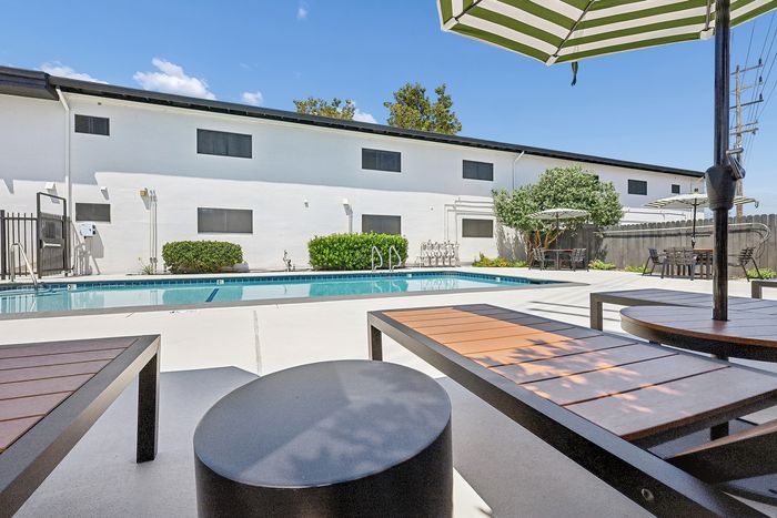 Inviting pool area with stylish lounge chairs and striped umbrellas, perfect for relaxation and social gatherings.