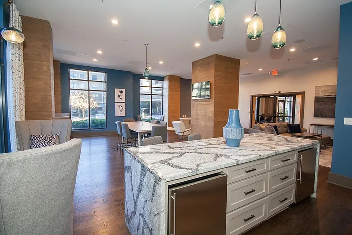 Modern open-concept apartment with elegant marble island, stylish pendant lighting, and spacious dining area with large windows.