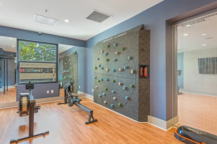 Modern fitness room featuring a cutting-edge climbing wall and state-of-the-art rowing machines, perfect for an invigorating workout.