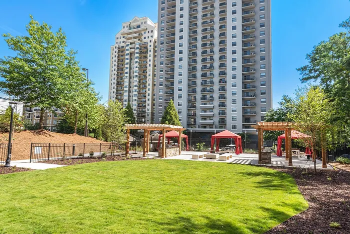 Luxurious high-rise apartment with expansive green space, featuring inviting outdoor cabanas and lush landscaping.
