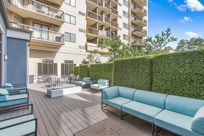Chic outdoor terrace featuring modern seating, lush greenery, and a cozy lounging area against a stylish apartment backdrop.