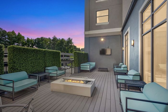 Luxurious outdoor lounge featuring cozy seating, built-in fire pit, and evening ambiance under a vibrant sunset sky.