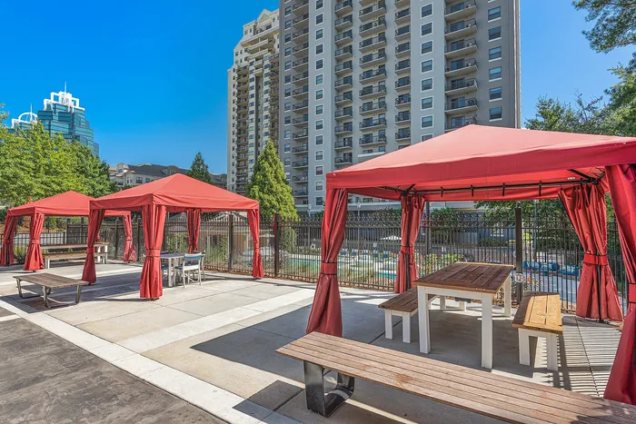 Vibrant outdoor space with modern red canopies, communal seating, and high-rise apartment views.
