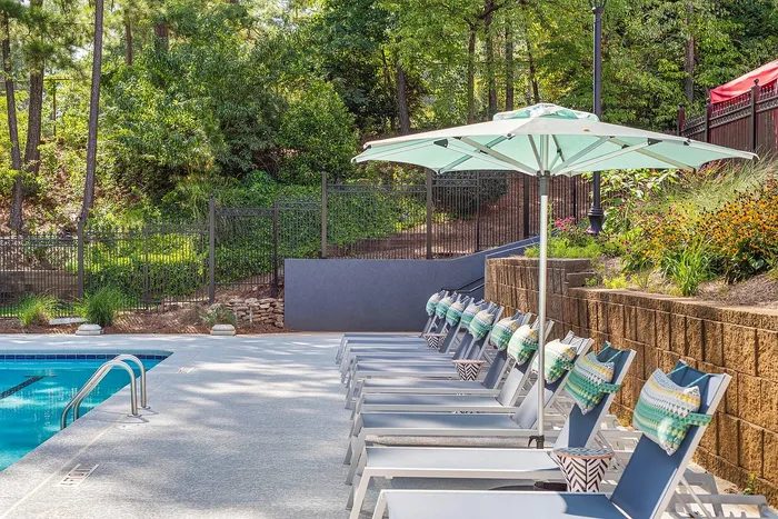 Inviting poolside retreat with comfortable loungers, vibrant umbrellas, and lush greenery, perfect for relaxation and leisure.