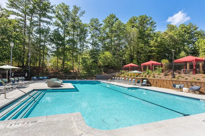 Luxurious outdoor pool area surrounded by lush greenery and elegant red cabanas, perfect for relaxation and leisure.