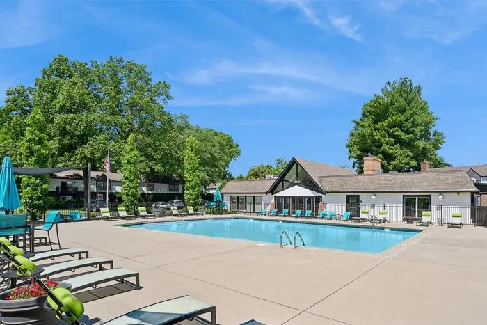 Inviting outdoor pool area with modern loungers and lush greenery, ideal for relaxation and entertainment.