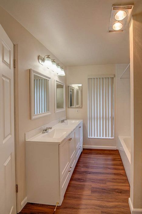 Elegant bathroom with modern double sinks, sleek mirrors, and warm wood flooring.